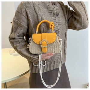 Détail d'un sac en paille avec rabat en cuir jaune et boucle florale dorée élégante