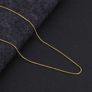 Macro shot of gold snake chain necklace with smooth metallic links on black leather