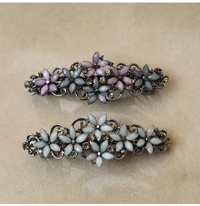 Detail view of vintage alloy hair clips with purple and blue resin flowers and rhinestones