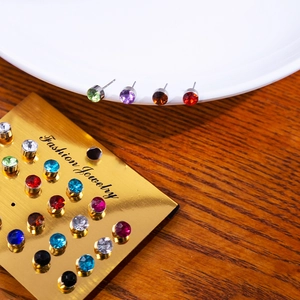 Set of 12 pairs multi-color sparkling stud earrings on gold card and ceramic plate