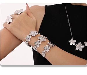 Close-up of a silver floral jewelry set featuring a necklace, bracelet, and ring on a model