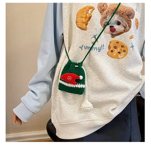 Detailed view of a handmade green crochet Christmas reindeer bag worn on a grey sweatshirt