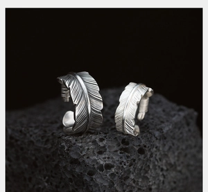 Macro shot of vintage silver feather rings with detailed carving on volcanic stone