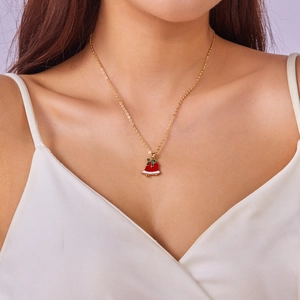 Golden Christmas necklace featuring a red bell pendant with green bow on female model