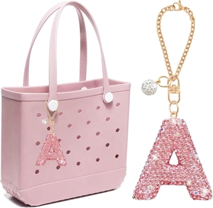 Close-up of pink rhinestone letter A charm with gold chain on a pink beach bag