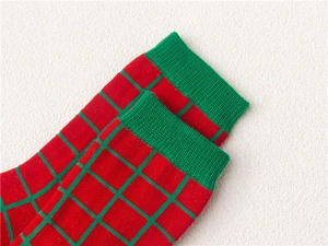 Red and green checkered Christmas cotton socks with knitted texture and warm fabric