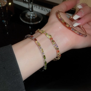 Macro shot of colorful gemstone bracelets and bangles stacked on a model's wrist