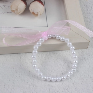 Detail of children's faux pearl bracelet featuring a soft pink organza ribbon bow