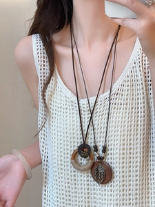 Layered ethnic bohemian necklaces with wooden ring and hollow leaf charms on model.