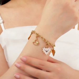Bracciale a catena dorata con ciondoli a cuore in smalto colorato sul polso di una donna