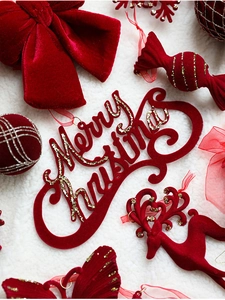 Close-up of red flocked Christmas ornaments with gold glitter on white plush background