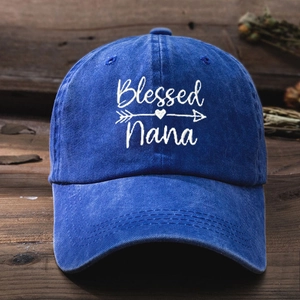 Close-up of Blessed Nana embroidery on a washed blue denim baseball cap over wood