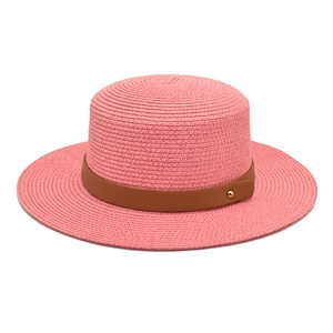 Detailed weave of a pink flat top straw hat featuring a brown leather band and gold stud