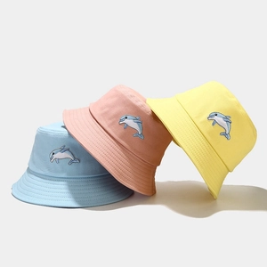 Trois bobs en coton colorés avec broderie de dauphin en bleu, rose et jaune