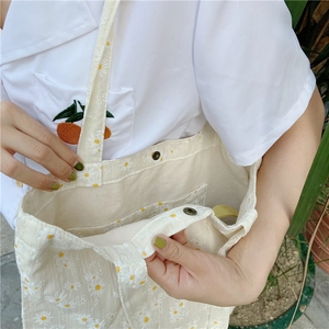 Close-up of daisy print canvas tote bag featuring magnetic buckle and inner pocket