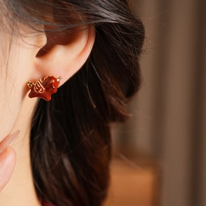 Close-up of model wearing small horse earrings with 18k gold plating and enamel