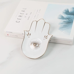 Nahaufnahme der Hamsa-Hand-Keramikschale für Schmuck mit goldenem Auge-Motiv