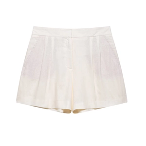 Detail of high-waist beige shorts showing premium pleated texture and wide-leg tailoring