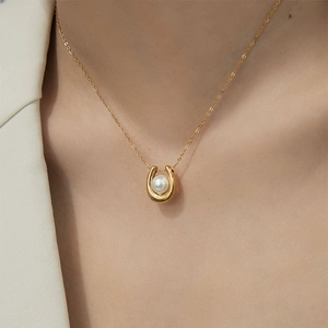 Elegant gold U-shaped horseshoe pendant necklace with white pearl on a female model