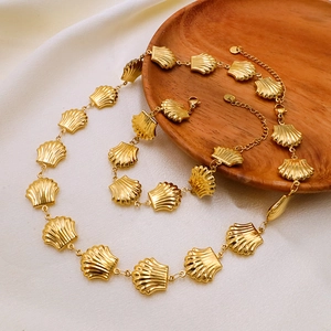Detail view of golden seashell charm necklace and bracelet set with textured metal finish