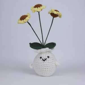 Handmade crochet sunflower plant in a white pot with smiling face and green leaves