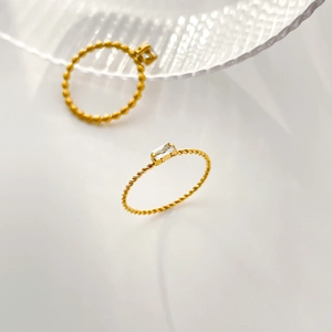 Detail of gold titanium rings featuring twisted and beaded bands with square zircon stones
