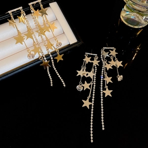 Boucles d'oreilles étoiles dorées avec pampilles en strass sur fond noir brillant
