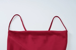 Detail of red satin dress featuring slim spaghetti straps and flat neckline