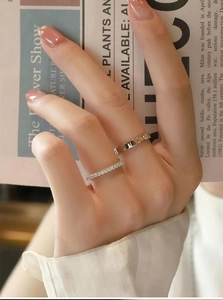 Detail of minimalist zircon band and geometric hollow gold ring on lifestyle background