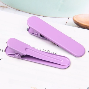 Close-up of two purple matte metal hair clips on white card with decorative text