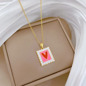 Elegant gold titanium necklace with pink square pendant featuring a red heart on silk