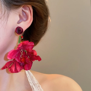 Detail shot of oversized red fabric flower tassel earrings worn on model for a sweet aesthetic