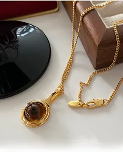 Detailed close-up of a gold-plated necklace with a brown smoky quartz pendant and lobster clasp