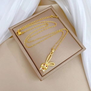 Detailed close-up of a golden rabbit necklace with clear zircons in a beige jewelry box