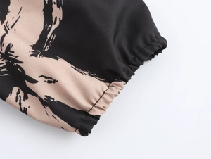 Detailed close-up of elastic cuffs on a black dress with beige abstract brush patterns