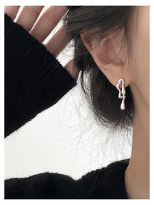 Close-up of asymmetric liquid metal silver stud earrings worn with a minimalist style