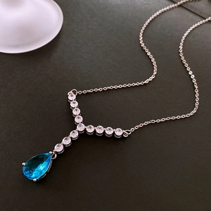 Close-up of Y-shaped silver necklace featuring blue teardrop pendant and zircon accents