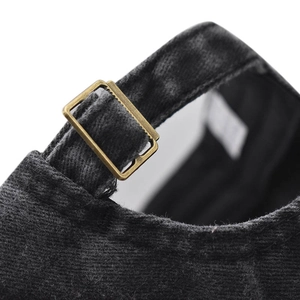 Detail of adjustable antique bronze metal buckle on black washed corduroy baseball cap