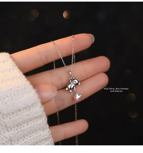 Detailed close-up of S925 sterling silver bear and star pendant on a fine cross chain