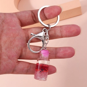 Detail of a clear glass wishing bottle keychain with red liquid and a pink stopper