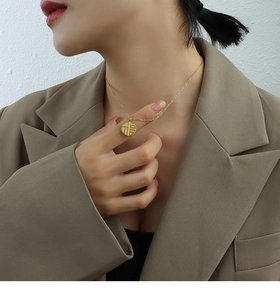 Detail of a 18K gold-plated titanium steel necklace with a lucky Fu character pendant