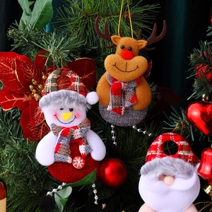 Detail of fabric Santa, Snowman, and Reindeer ornaments hanging on a Christmas tree