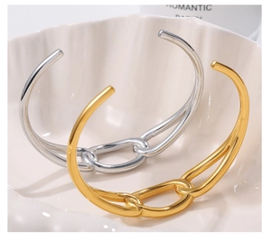 Close-up of gold and silver interlocking chain link bangles on a seashell tray