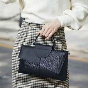 Elegant black top-handle bag featuring crocodile texture and smooth leather finish