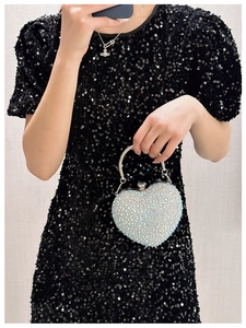 Close-up of sparkling heart-shaped evening bag with silver rhinestones held by a model