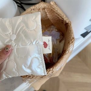 Close-up of white quilted heart pattern sanitary napkin pouch with snap button closure