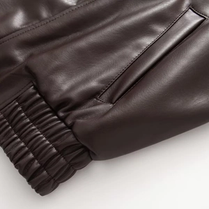 Detail of dark brown leather jacket featuring side pocket and elastic ribbed hem