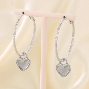 Detail of silver heart lock charms on hoop earrings displayed on a pink velvet T-stand