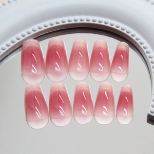 Pink gradient cat-eye press-on nails in long coffin shape displayed on mirror surface