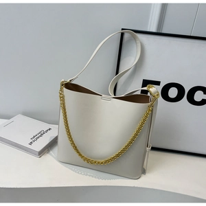 Detail of white tote bag stitching and golden chain strap on a minimalist bucket bag
